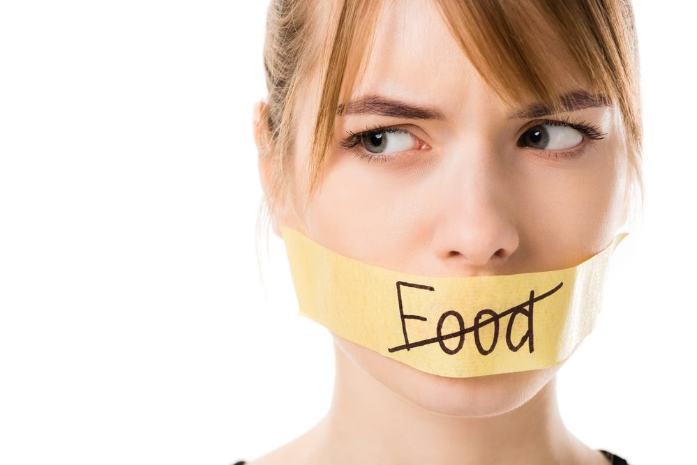 Woman with eating disorder and tape over mouth